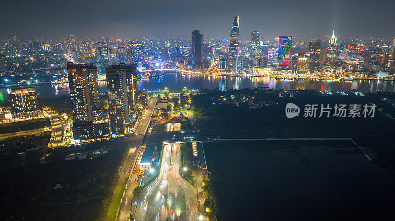 空中夜景的Bitexco塔，建筑，道路，Thu Thiem 2桥和西贡河在胡志明市-远处是地标81摩天大楼